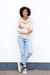 © mimagephotos - Full body smiling african american woman with arms crossed against white wall