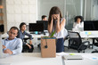 © fizkes - Desperate dismissed woman holding head in hands at workplace, upset female employee pack belongings in cardboard box, feeling stressed about job loss, unexpected undeserved dismissal, discrimination