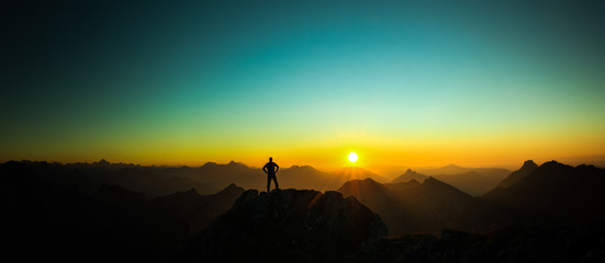 Poster - Man reaching summit enjoying freedom and looking towards mountains sunrise.