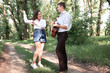 © soleg - young couple walking in the forest, playing guitar and dancing, summer nature, bright sunlight, shadows and green leaves, romantic feelings