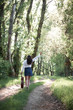 © soleg - young woman walking in the forest and playing guitar, summer nature, bright sunlight, shadows and green leaves, romantic feelings