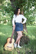 © soleg - young woman walking in the forest and playing guitar, summer nature, bright sunlight, shadows and green leaves, romantic feelings