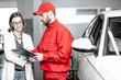 © rh2010 - Young woman client with auto mechanic in red uniform standing with some documents at the car service