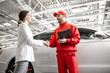 © rh2010 - Young woman client shaking hands with auto mechanic in red uniform having a deal at the car service