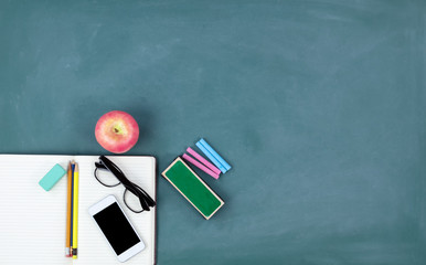 Back to school concept with basic stationery on a green chalkboard background