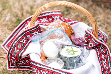 Wall Mural - Eggs and Kulich Russian Orthodox Easter blessing food straw basket, on grass ground outside at church, nobody