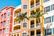 Condos, condominiums colorful, orange yellow multicolored buildings facade exterior with windows, palm trees, real estate property in Spain