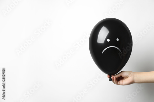 Fotomural Woman holding balloon with sad face on white background, space for text