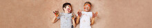 Panoramic Shot Of Little Cheerful Boys With Paint On Face And Hands Lying On Floor And Laughing