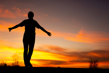 Wall Mural - Young woman relaxing in winter sunset sky outdoor.