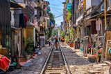 Fototapeta Uliczki - Woman is making a picture of Hanoi city railway Perspective view running along narrow street with houses in Vietnam