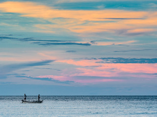 Wall Mural - Fishermen out at sea at sunset
