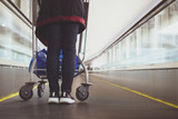 Fototapeta Tulipany - Close up woman with luggage trolley in airport escalator