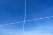 Kreuz Kondensstreifen vor blauem Himmel