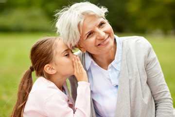 Sticker - family, trust and people concept - happy granddaughter whispering secrets to grandmother at summer park