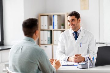 Poster - medicine, healthcare and people concept - smiling doctor talking to male patient at medical office in hospital