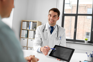 medicine, healthcare and technology concept - happy doctor with tablet pc computer and male patient talking at medical office in hospital