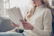 Cropped profile side view portrait of nice lovely attractive wavy-haired lady housewife wearing sweater holding in hands reading digest in light interior room