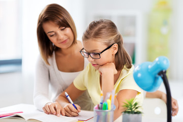 Canvas Print - education, family and learning concept - mother and daughter doing homework together at home