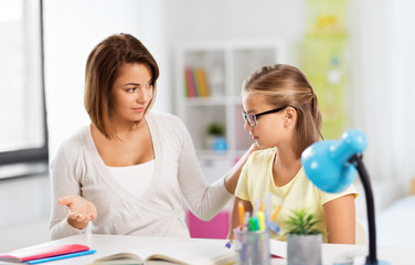 Wall Mural - education, family and learning concept - displeased mother talking to daughter while doing homework at home