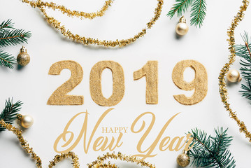 Wall Mural - top view of 2019 year sign, pine branches, golden garlands and christmas balls on white background w