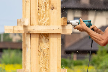 Wall Mural - Close up cropped photo of drill instrument in worker hand. He using tool to make hole in wooden pole construction or column formwork