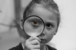  black and white creative portrait of a five-year-old girl who carefully looks at a magnifying glass