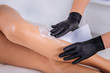 © Viacheslav Yakobchuk - Close up of master in hair removal wearing gloves striping wax away