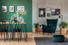 Elegant Bottle Green Dining Room With Wooden Table With Black Chairs And Emerald Green Armchair And Pouf