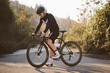 Professional road bicycle racer posing. Men cycling mountain road bike at sunset.