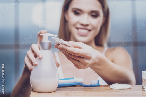 Fotografía Delighted woman squeezing lotion into cotton pad