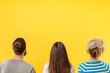 © golubovy - Back view of modern casual women and man standing in row against bright yellow background
