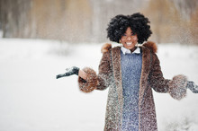 Curly Hair African American Woman Wear On Sheepskin Coat And Gloves Posed At Winter Day Throws Up Snow.