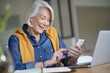 © goodluz - Attractive senior woman smiling and texting at home whilst working