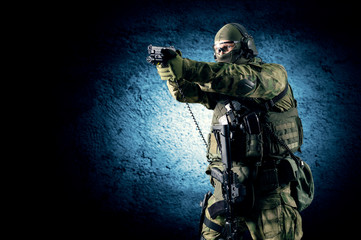 Special unit soldier stands with a pistol in his hands and aims at the target