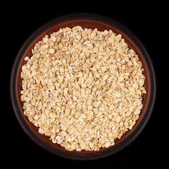 Wall Mural - Oatmeal flakes in a plate on a dark background