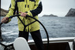 A sailing yacht skipper is at the helm. Close-up. It's cold, waves.