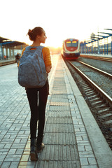 portrait of a young woman traveler with small backpack on the railway stantion