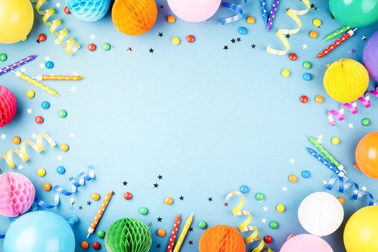 birthday party background on blue. top view. frame made of colorful serpentine, balloons, candles, c