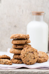 Chocolate oatmeal chip cookies with milk on the rustic wooden table.