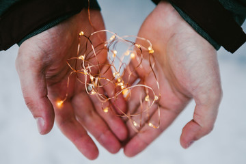 Man hands holding a row of lights in the dark to make a wish.