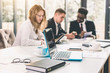 © sofiko14 - Group of happy diverse male and female business people in formal gathered around laptop computer in bright office