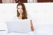 © dianagrytsku - Pretty young woman working on her laptop on her bed at home