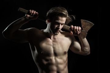 Portrait of attractive confident handsome man. Brave and serious young guy holding axe. Strict unshaven boy with cunning look is carrying ax on shoulders isolated on black background.