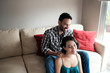 © Cavan Images - Smiling boyfriend massaging girlfriend's neck while sitting on sofa at home