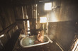 © Cavan Images - Naked woman with blond hair kneeling in bathtub