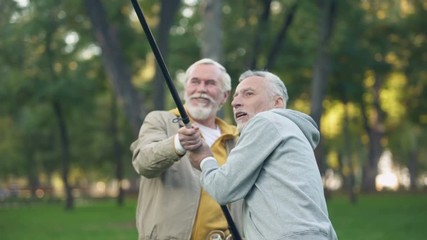 Wall Mural - Two pensioners catching big fish, pulling spinning together, friendship support