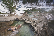Woman In Bikini Relaxing In Hot Spring In Forest During Winter