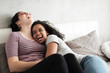 © Cavan Images - Happy lesbian couple laughing while relaxing on bed at home