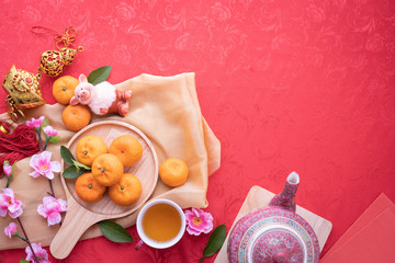 Wall Mural - Orange fruit, Pink cherry blossom and teapot with Copy space for text on red texture background, Chinese new year background.